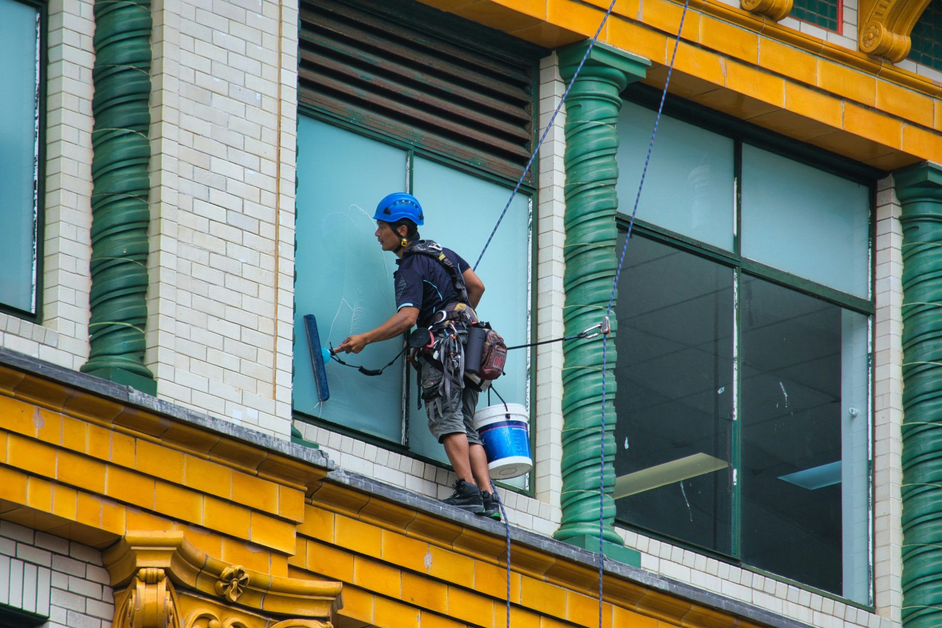 Ein Fensterputzer arbeitet hoch oben an der Fassade eines Gebäudes.